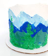 Blue and green mountain range cake with pine tree details